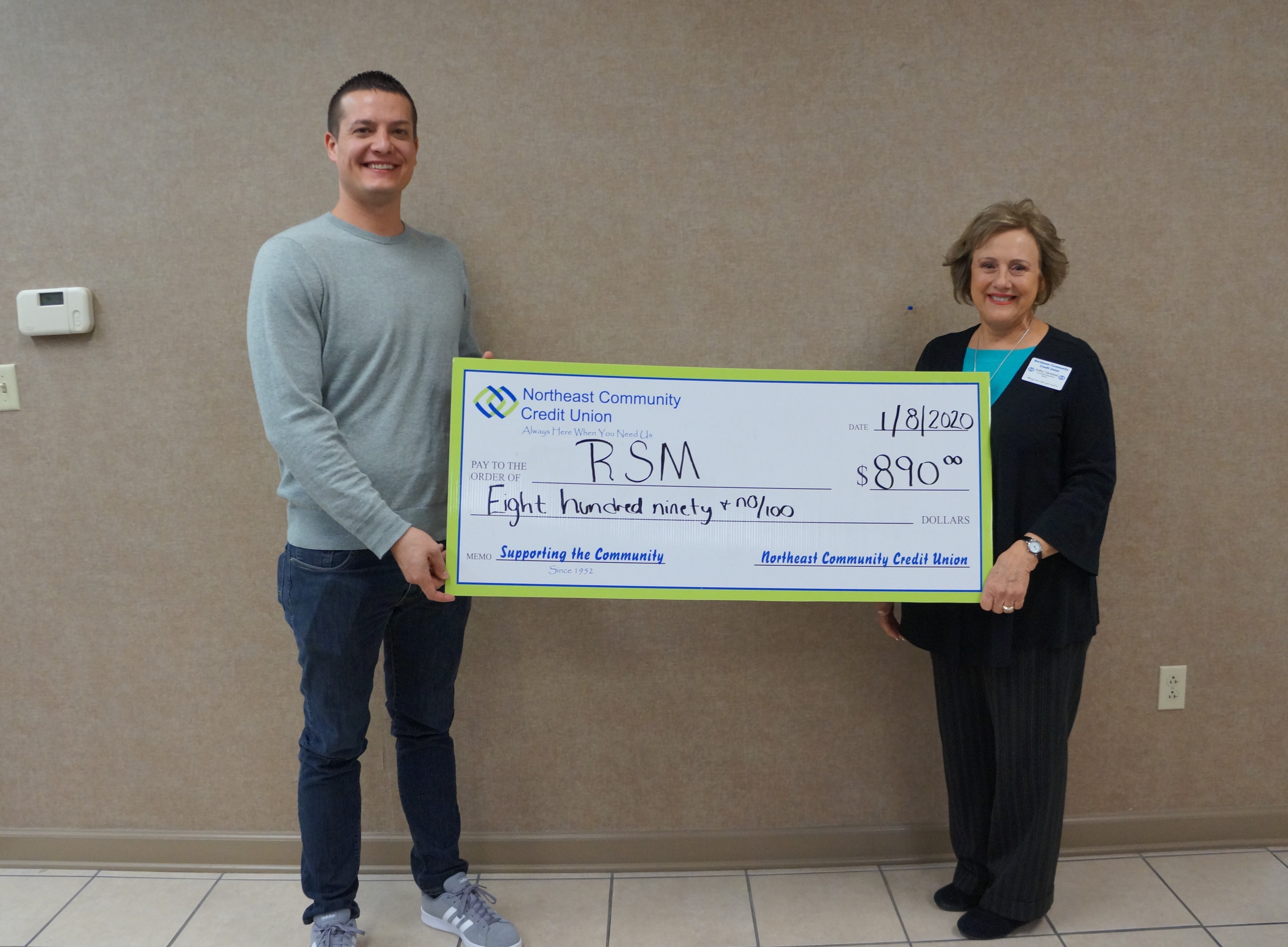 Man accepts donation check from woman